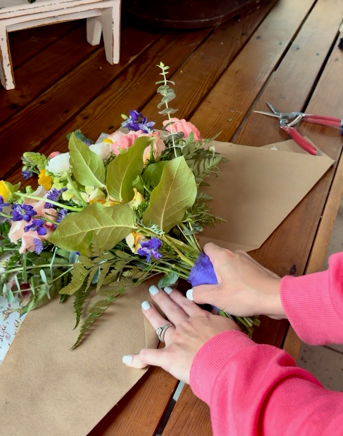 Hands wrapping a garden-style bouquet during a floral workshop