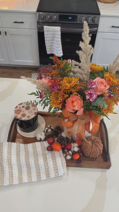 Amber Fields bouquet styled in a white pitcher while the florist arranges stems; vase and props not included